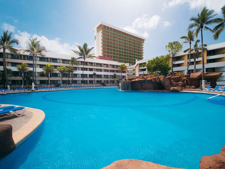Amplias piscinas conectadas con cascadas, formaciones rocosas y bar en la piscina