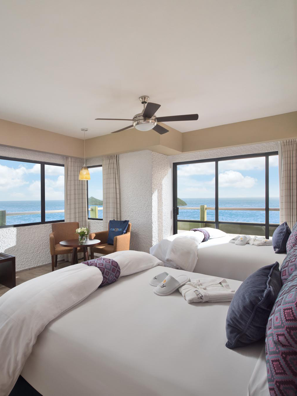 King beds with white sheets and large windows with ocean view
